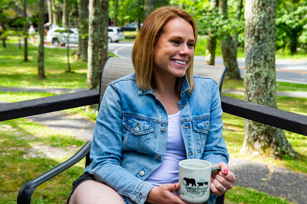 A guest at Lewis Mountain Cabins enjoying a cup of coffee on the porch